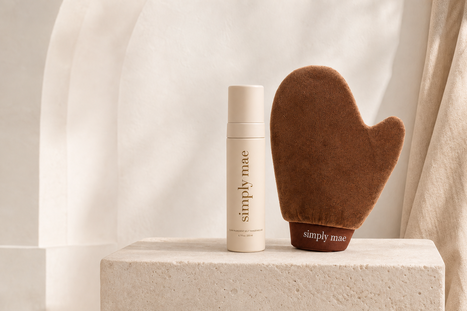 Simply Mae Glow Duo self-tanning mousse and velvet mitt on a cream stone pedestal